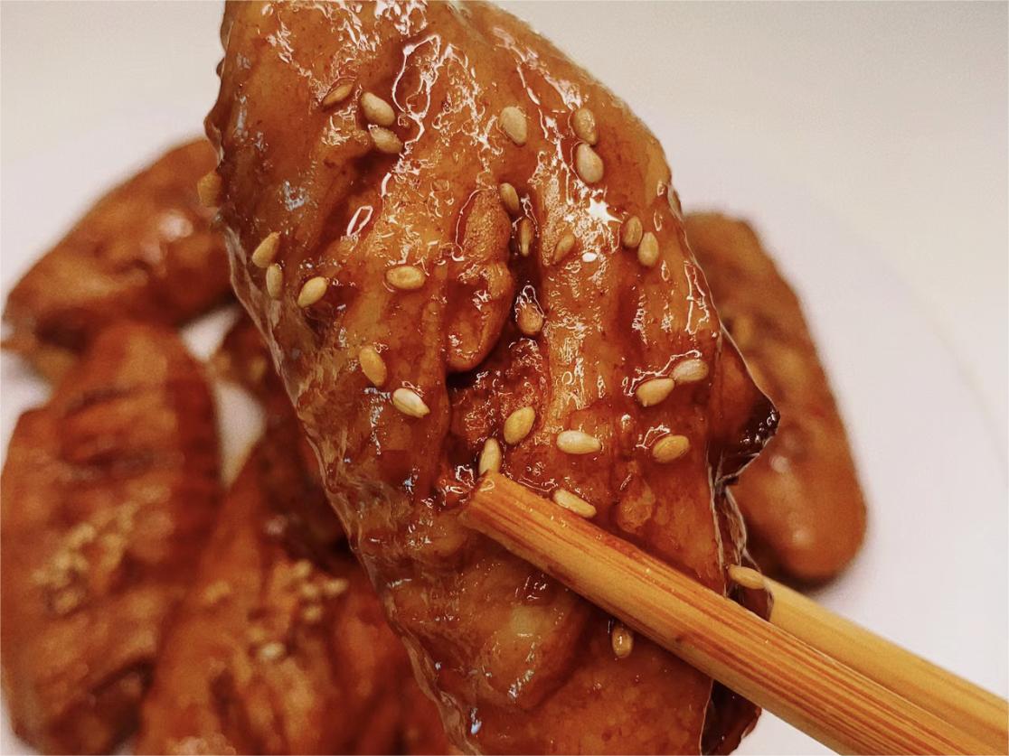A chicken wing picked up by chopsticks.